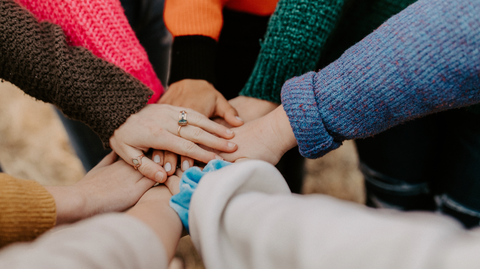 A group of people lay their hands on top of each other