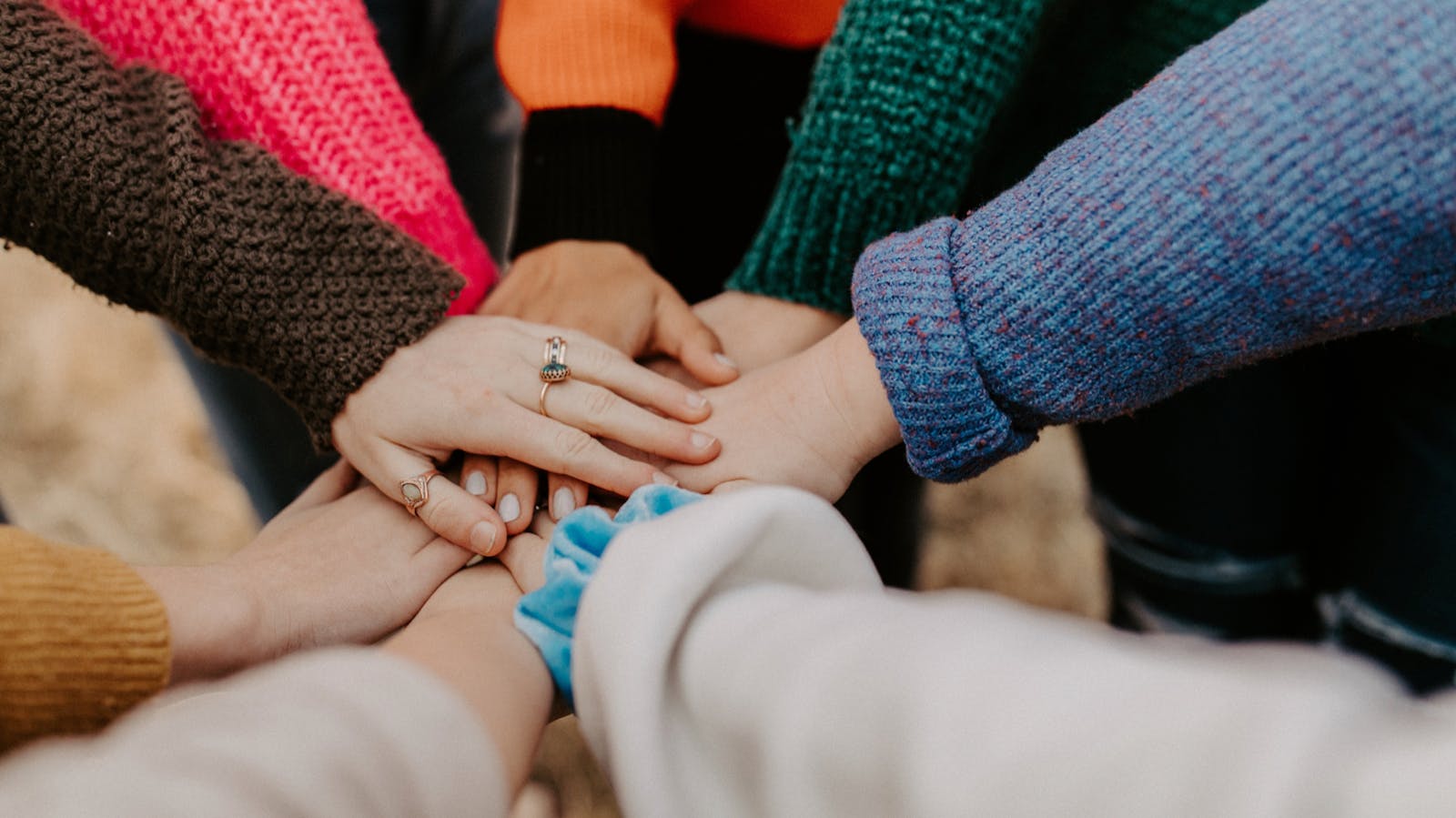 A group of people lay their hands on top of each other