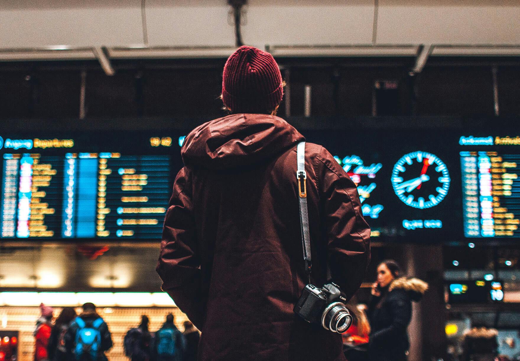 Man standing at an airport looking at signs