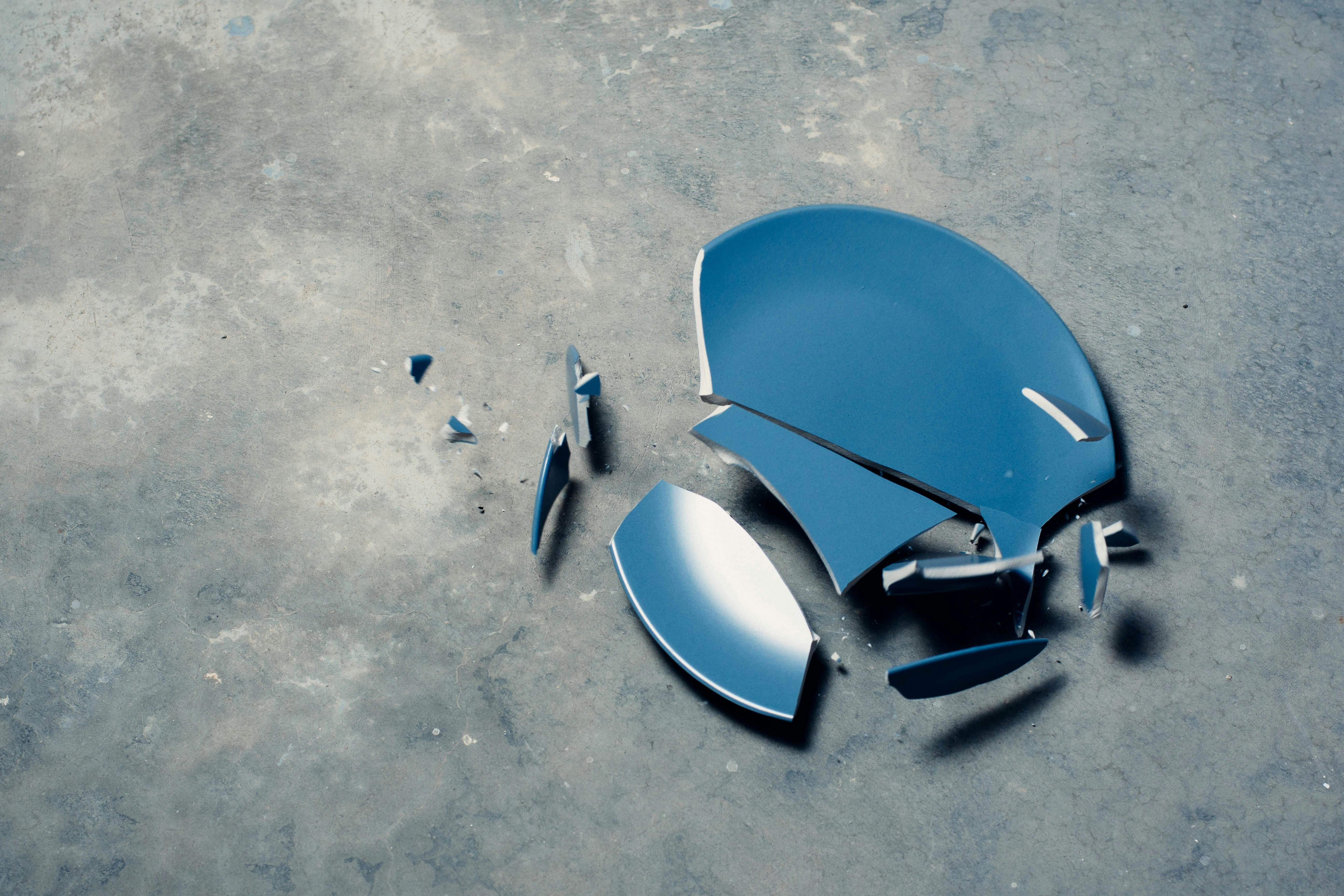 A blue plate breaking on a concrete floor