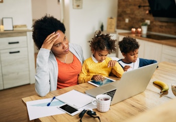 woman working with two children playing nearby