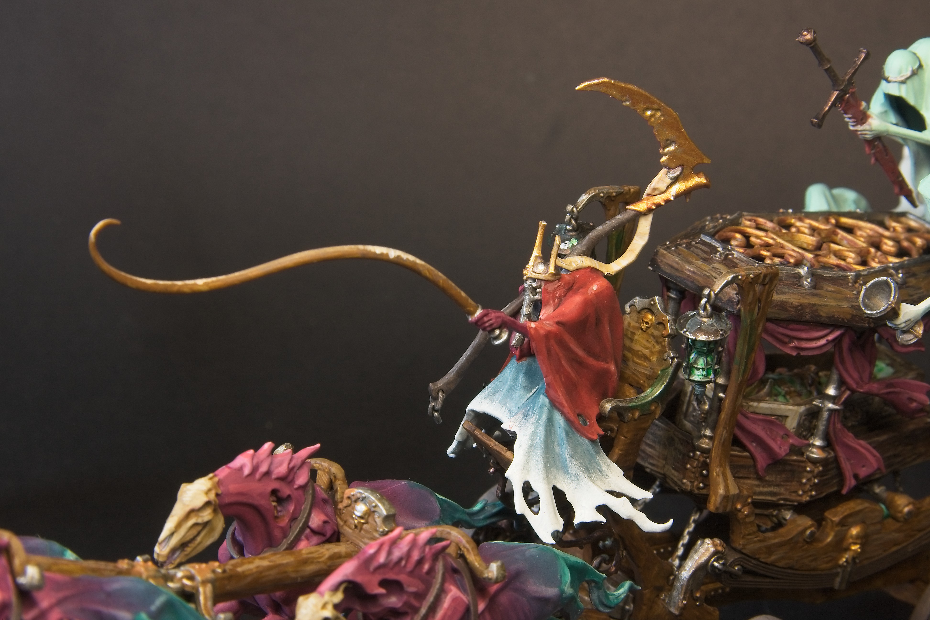 The black coach's rider wheres a red cloak, and carries a golden scythe and brown whip.