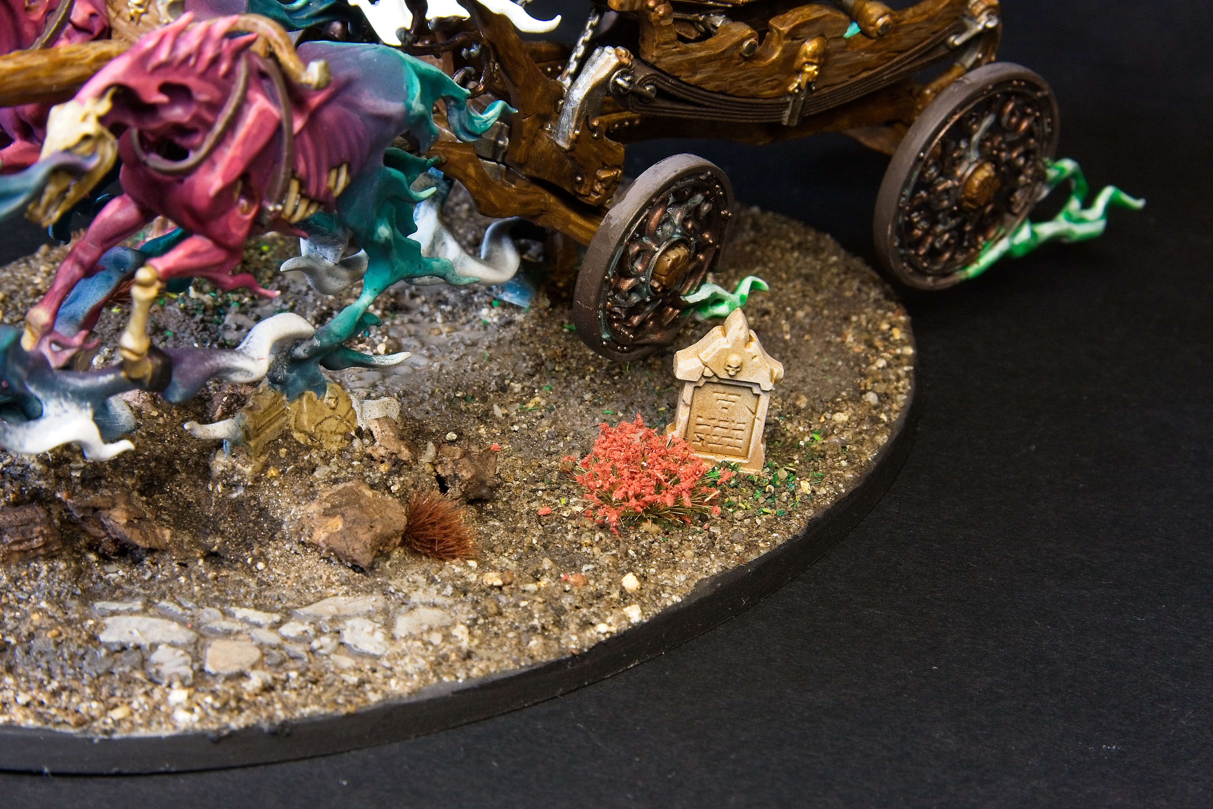 Some cobblestone, a patch of poppies, and a grave lay beside the black coach.