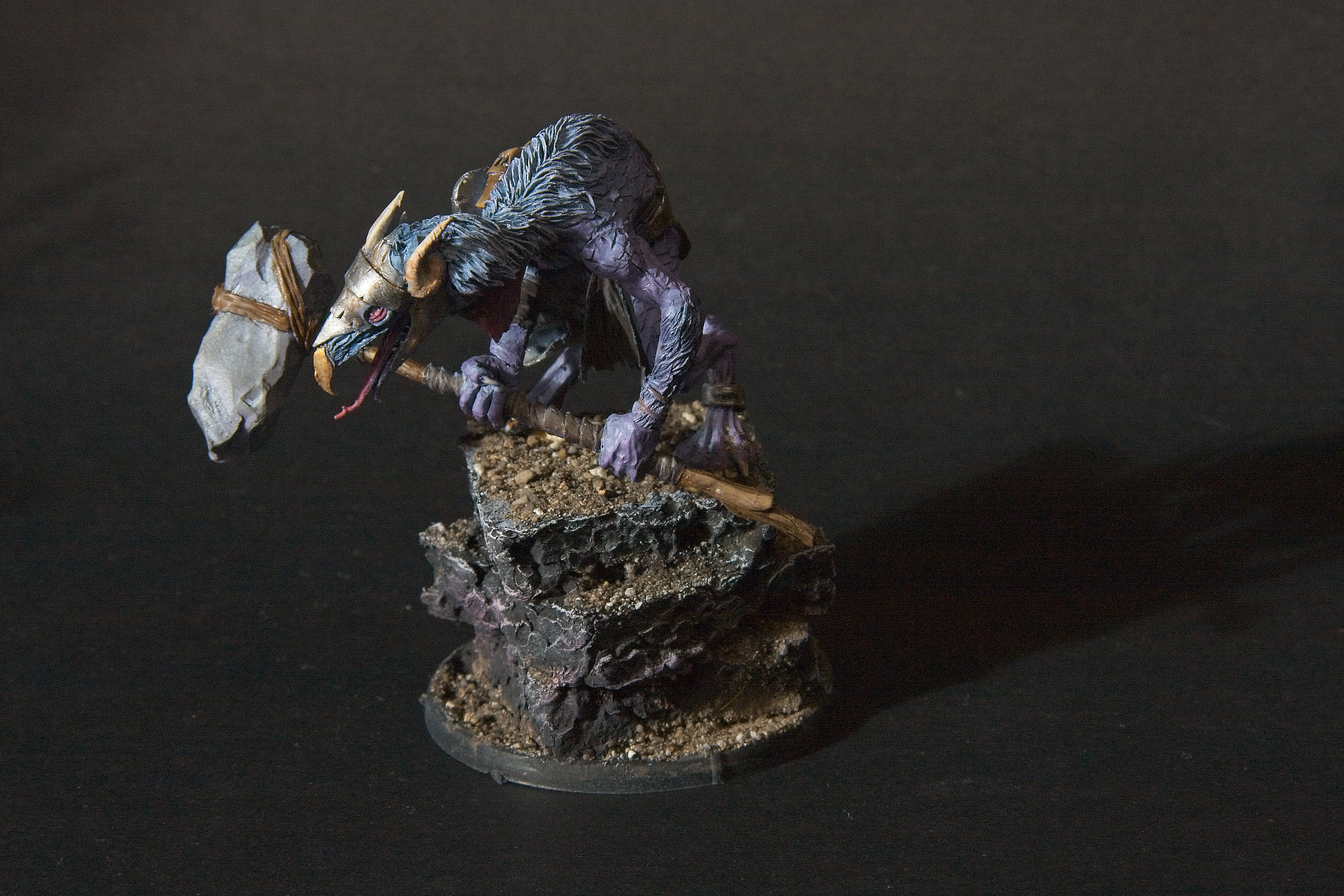 This bird-humanoid carries a hammer, with a loin-cloth and rusty scraps of metal for armor.