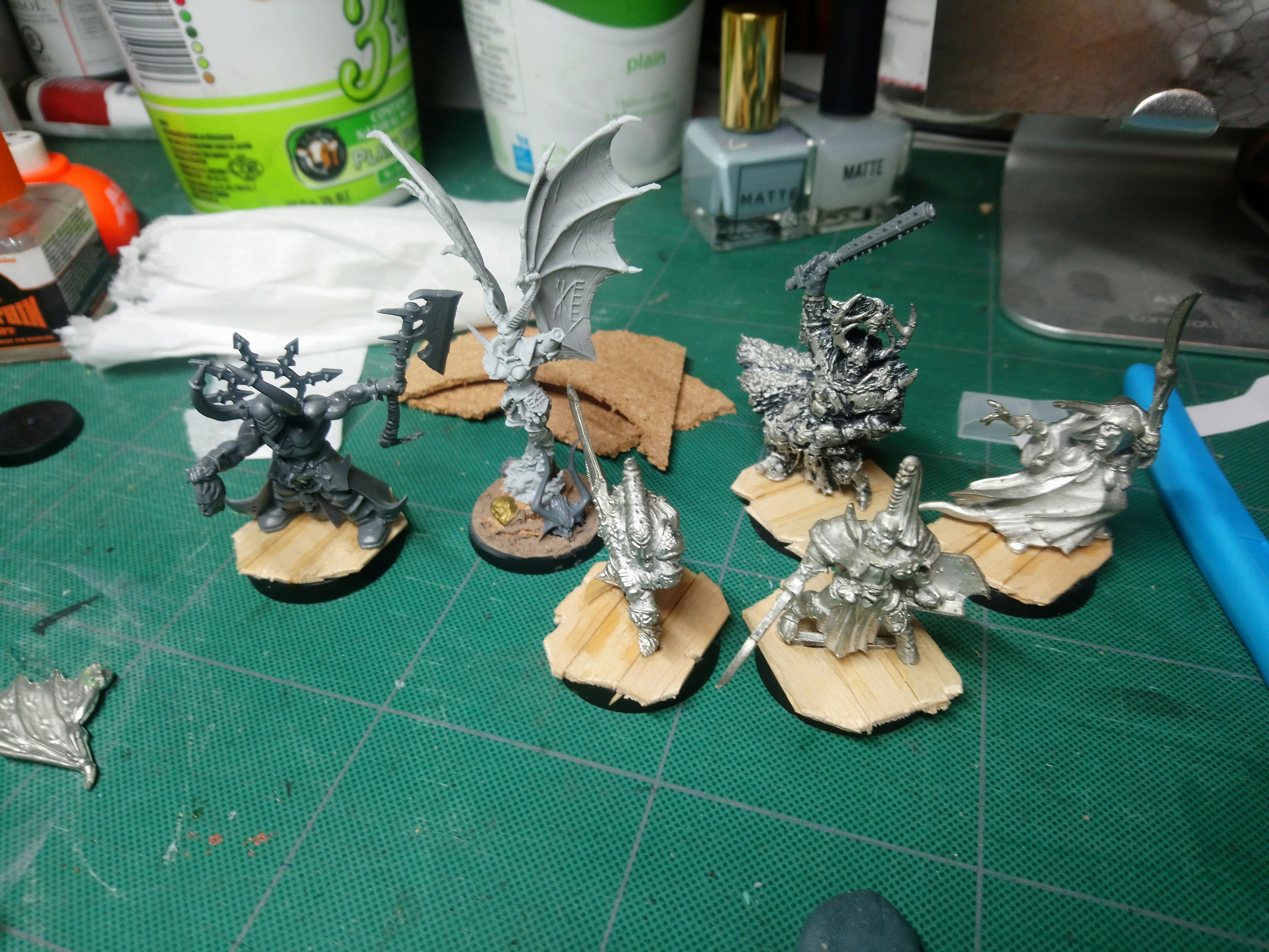 4 metal, 1 resin, and 1 plastic chaos minis on wood plank bases