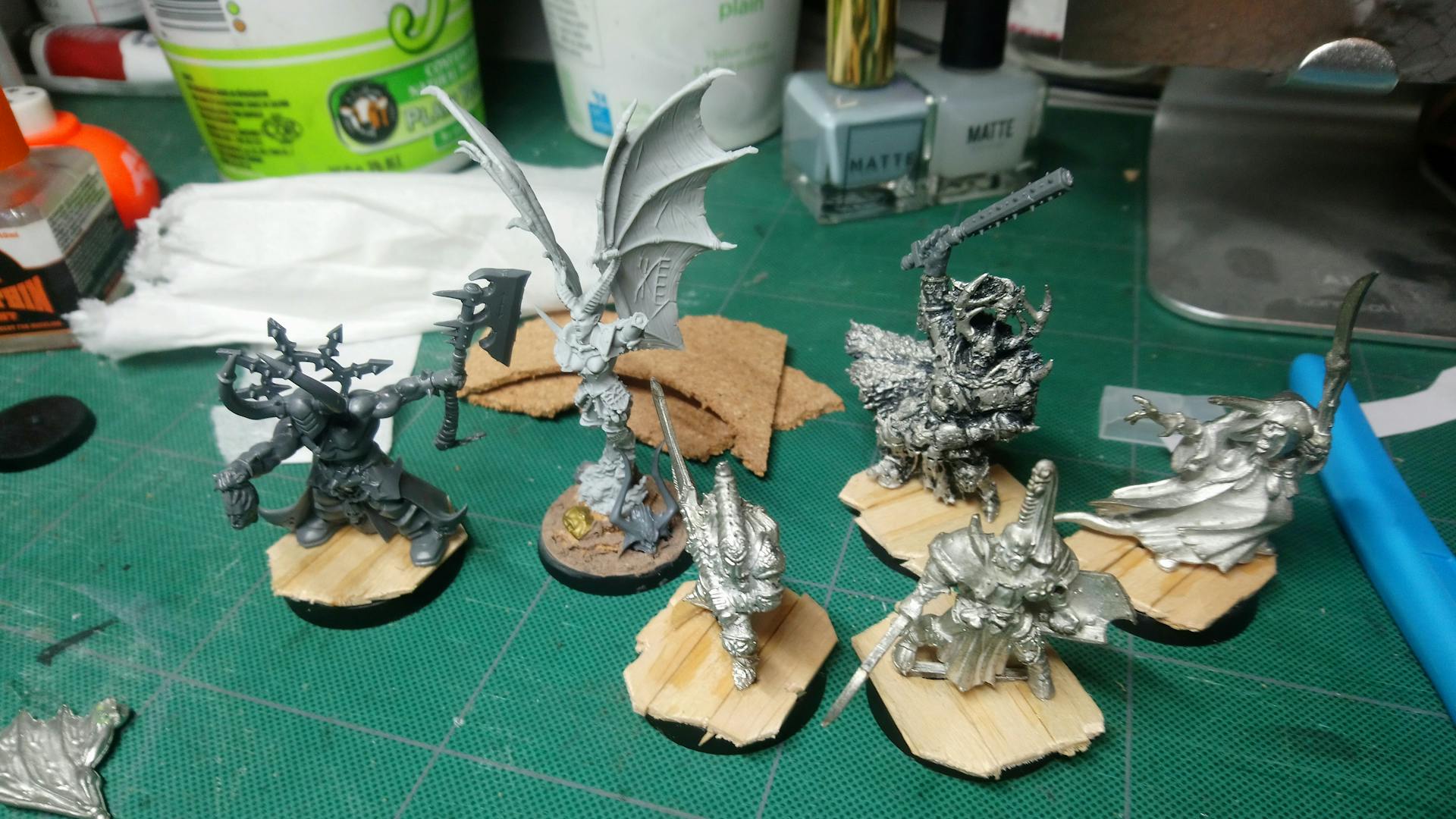 4 metal, 1 resin, and 1 plastic chaos minis on wood plank bases