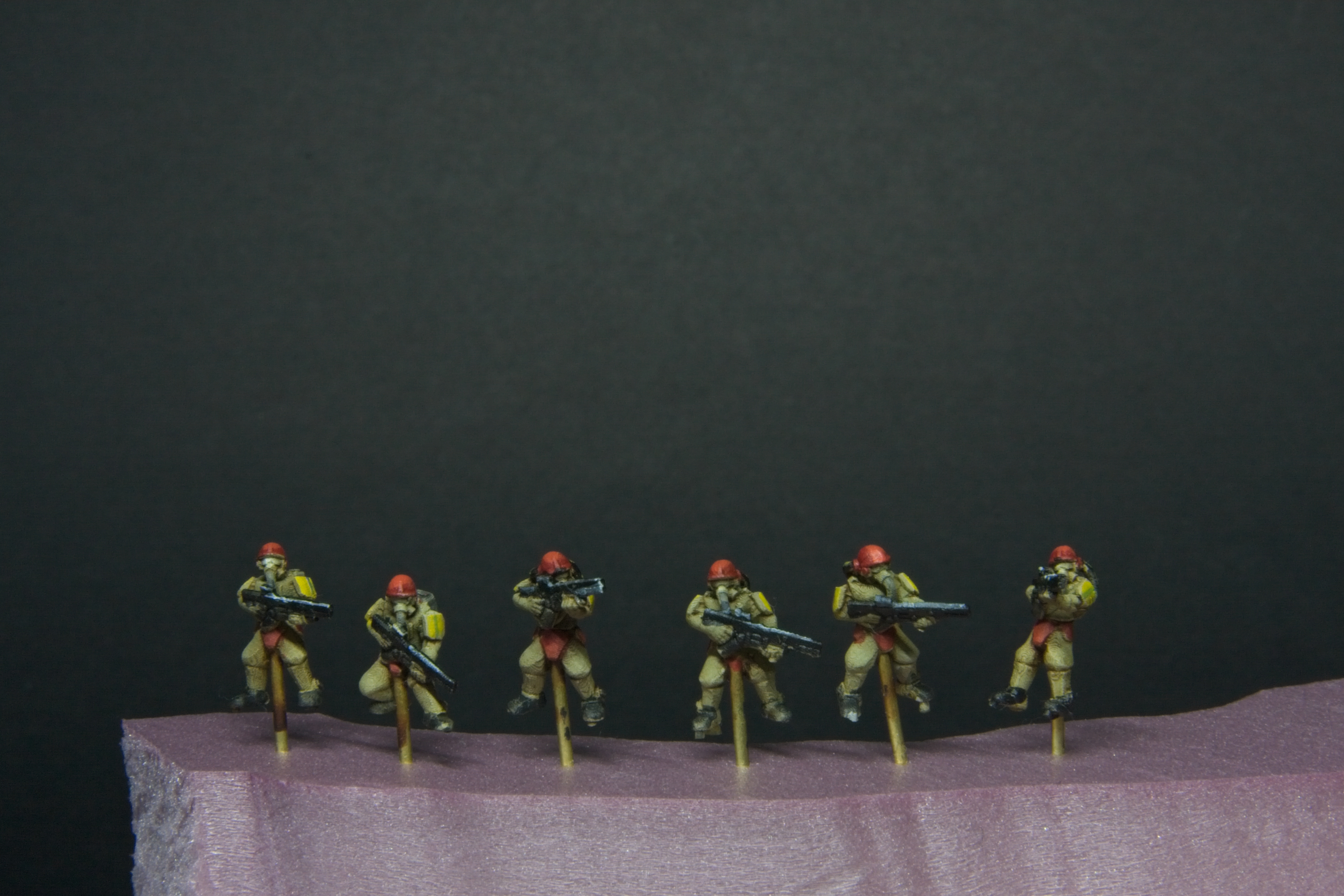 Tiny futuristic soldiers with yellow armor pads, and red helmets.