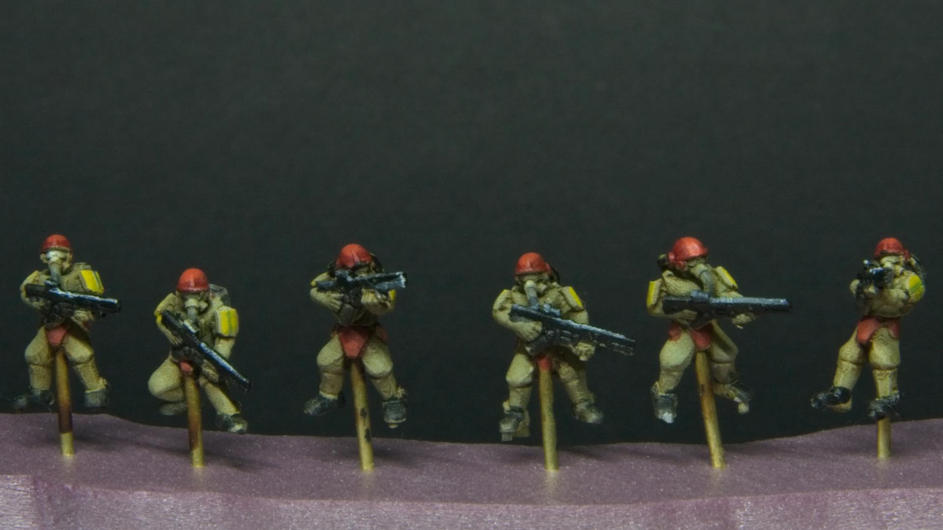 Tiny futuristic soldiers with yellow armor pads, and red helmets.