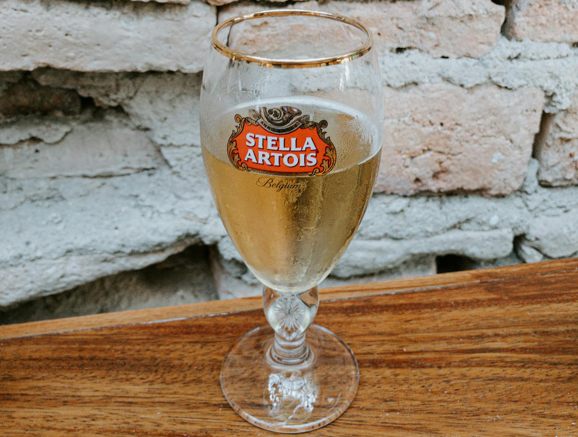 Glass of Stella Artois on table next to brick wall