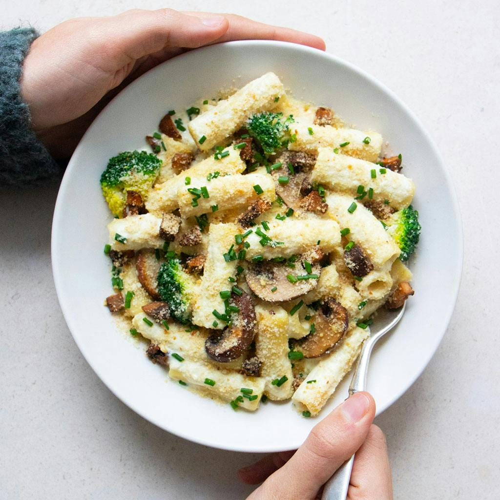 person holding bowl of carbonara