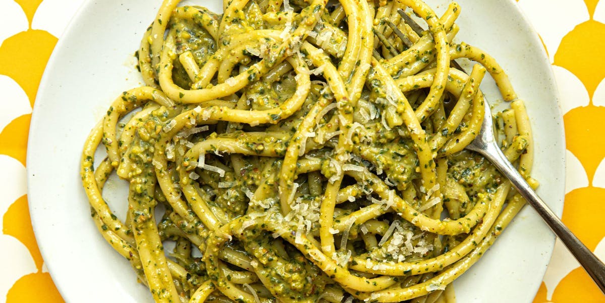 pesto pasta on white plate and yellow/white background