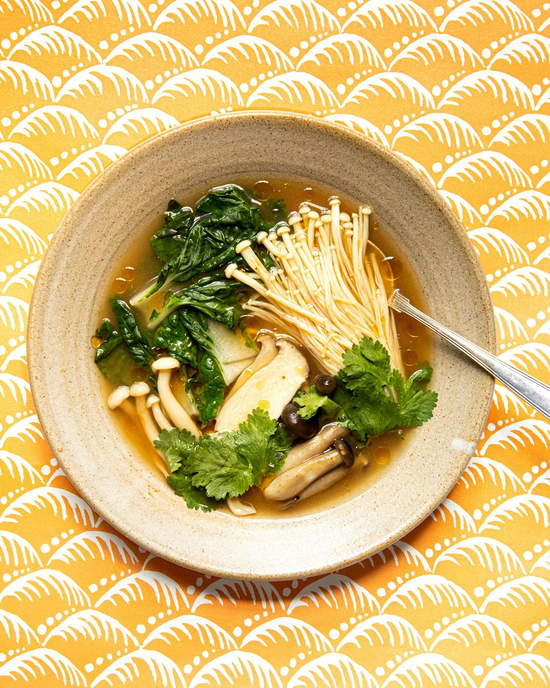 tom yum soup in bowl with spoon on yellow background