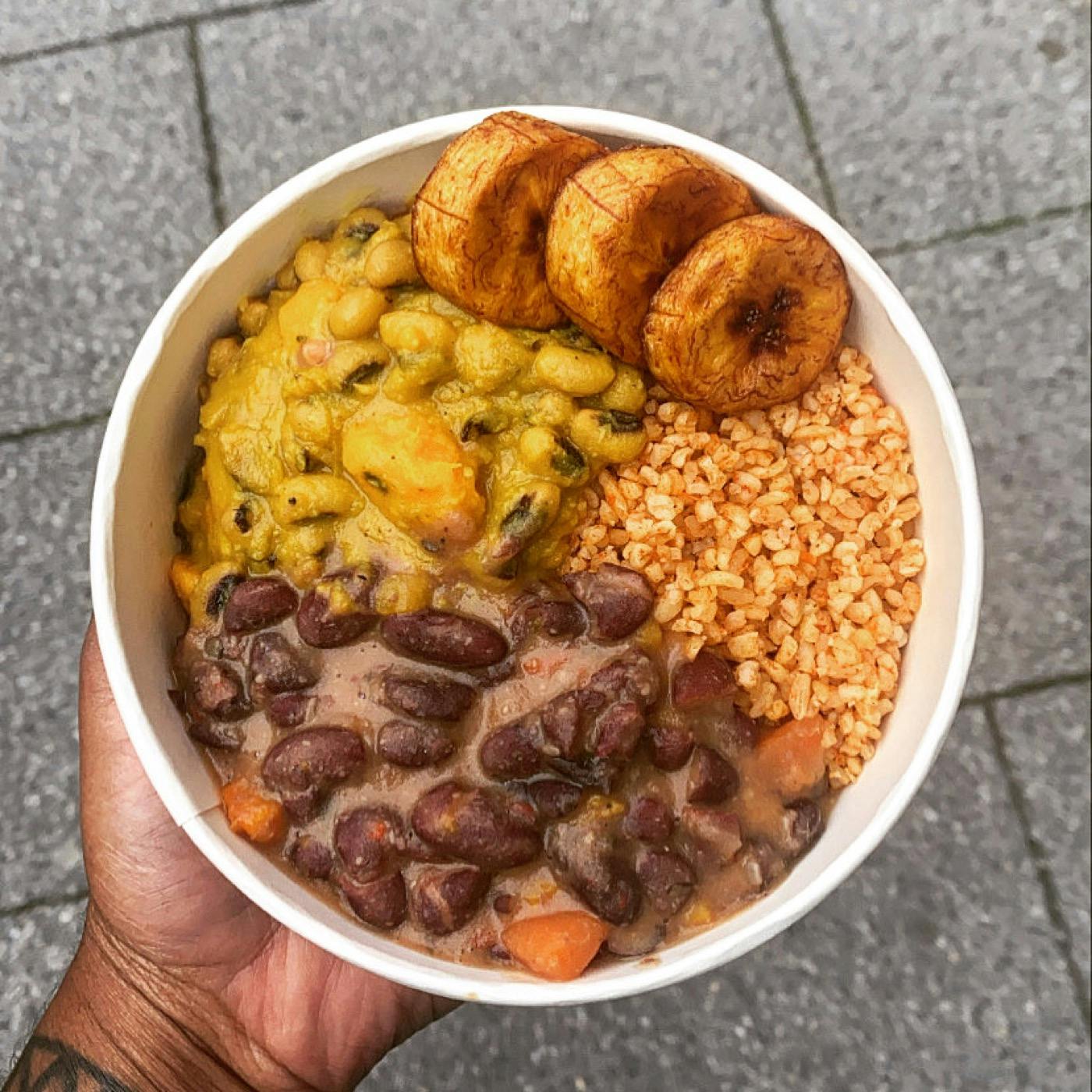 person holding bowl of vegan caribbean food