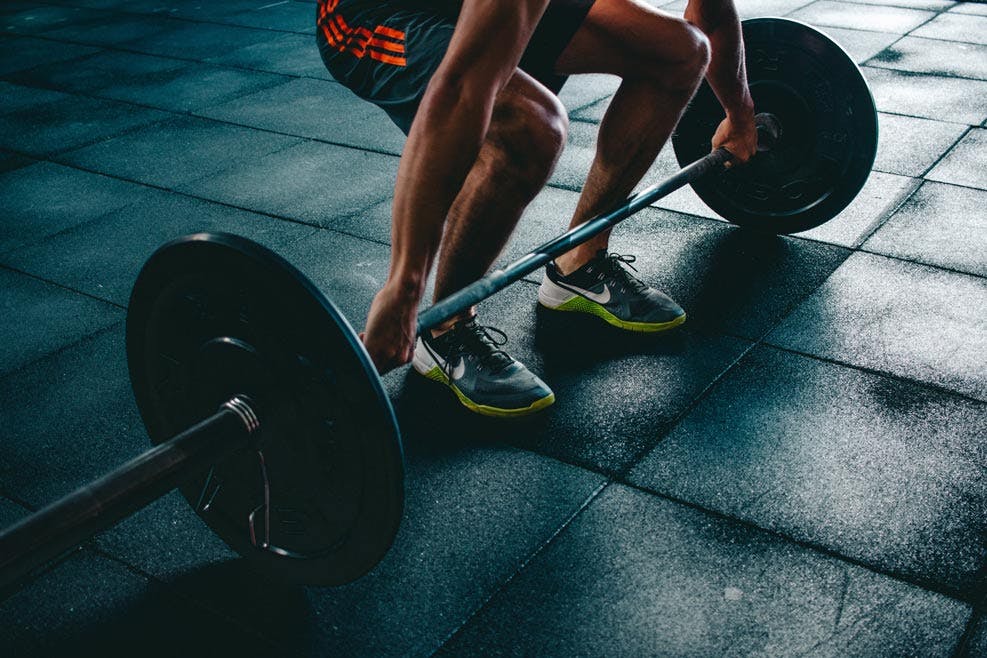 man lifting barbell with weights