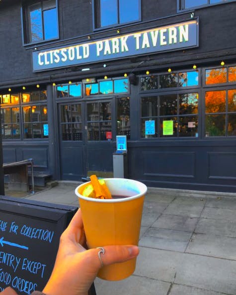 person holding mulled wine outside pub