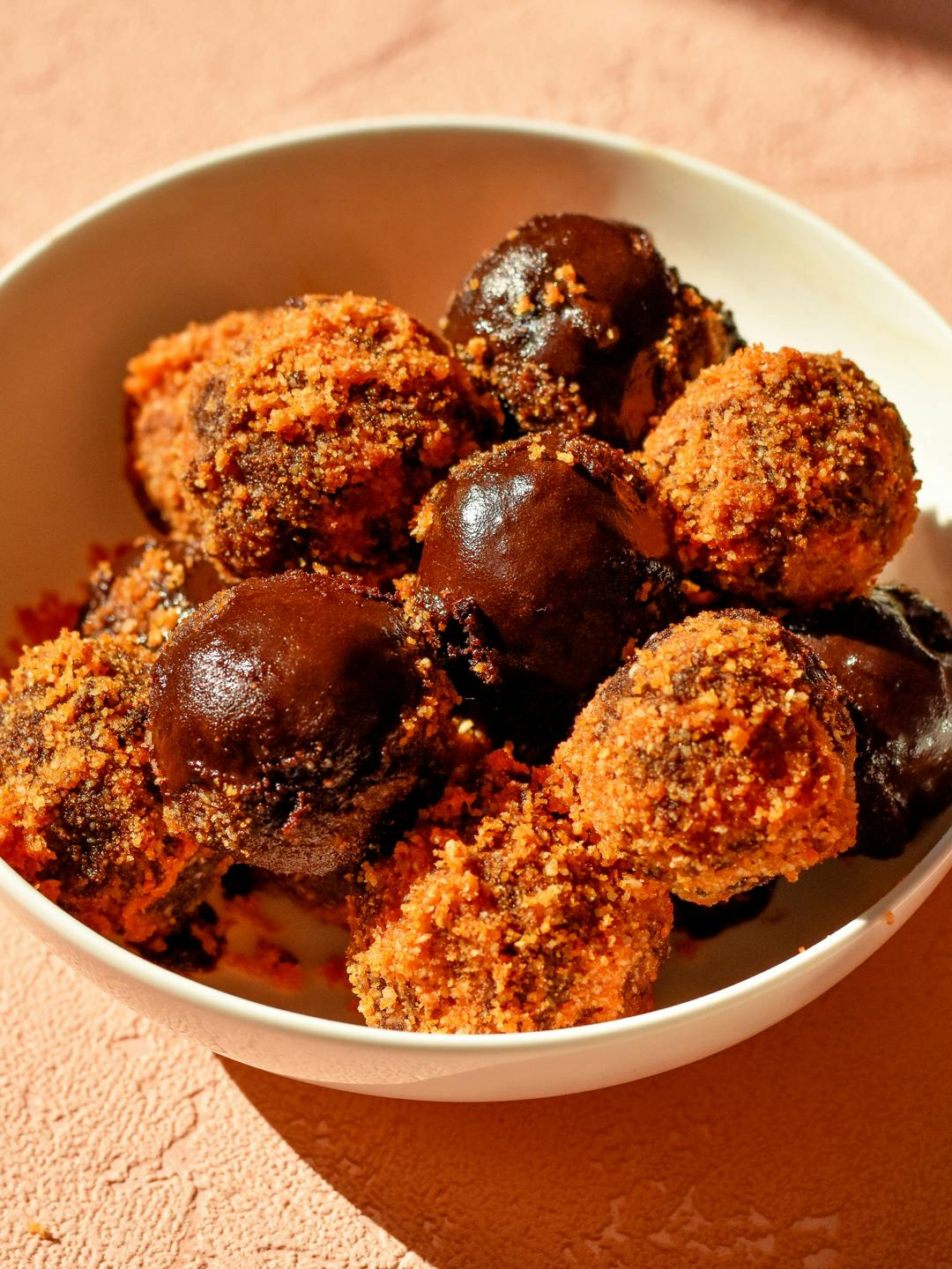 Vegan dunkin' donuts munchkins, with chocolate coating and butternut topping, in a bowl