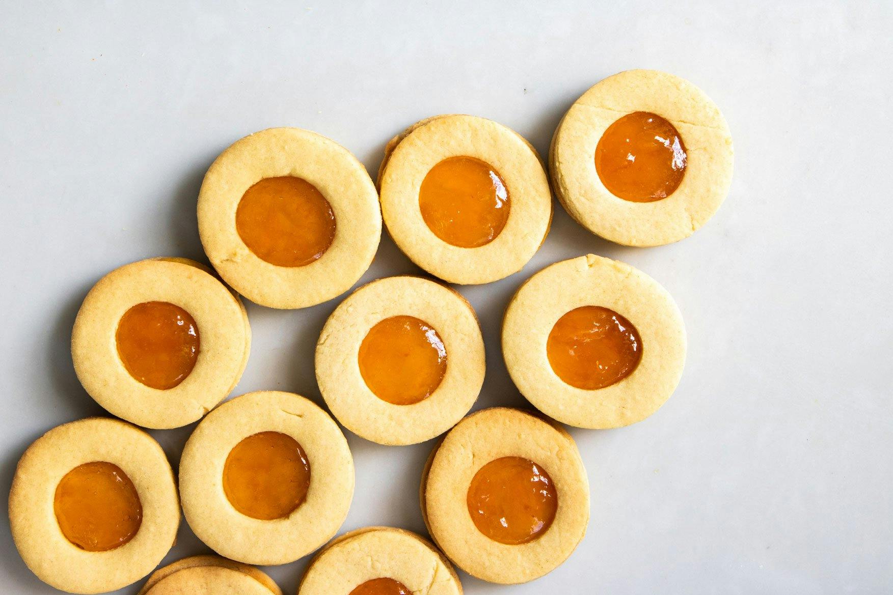 Close up image of apricot jam biscuits layed neatly next to each other on a table.
