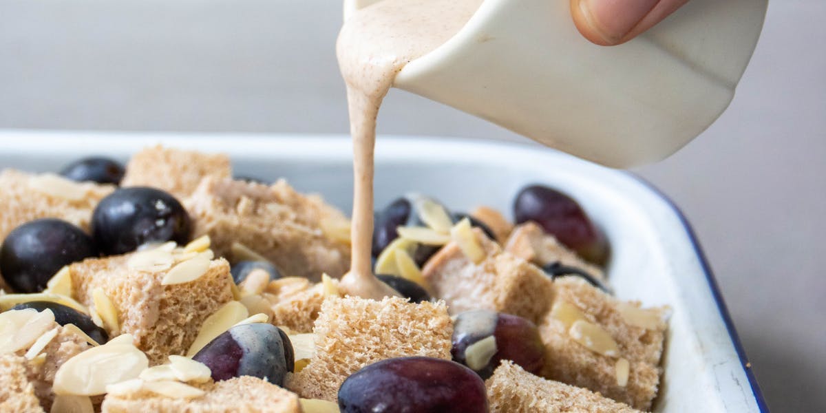 person pouring custard onto bread pudding