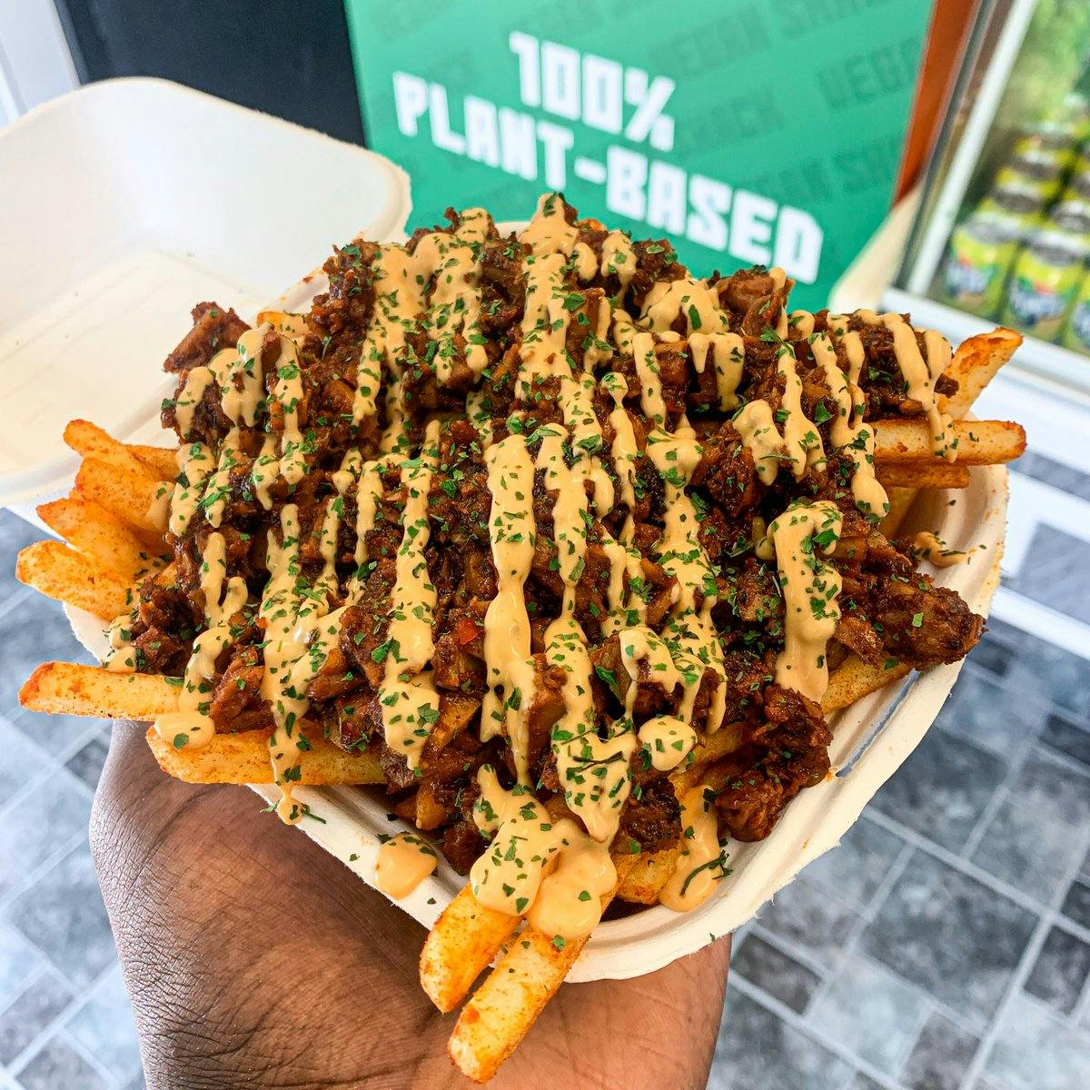 person holding plate of topped chips