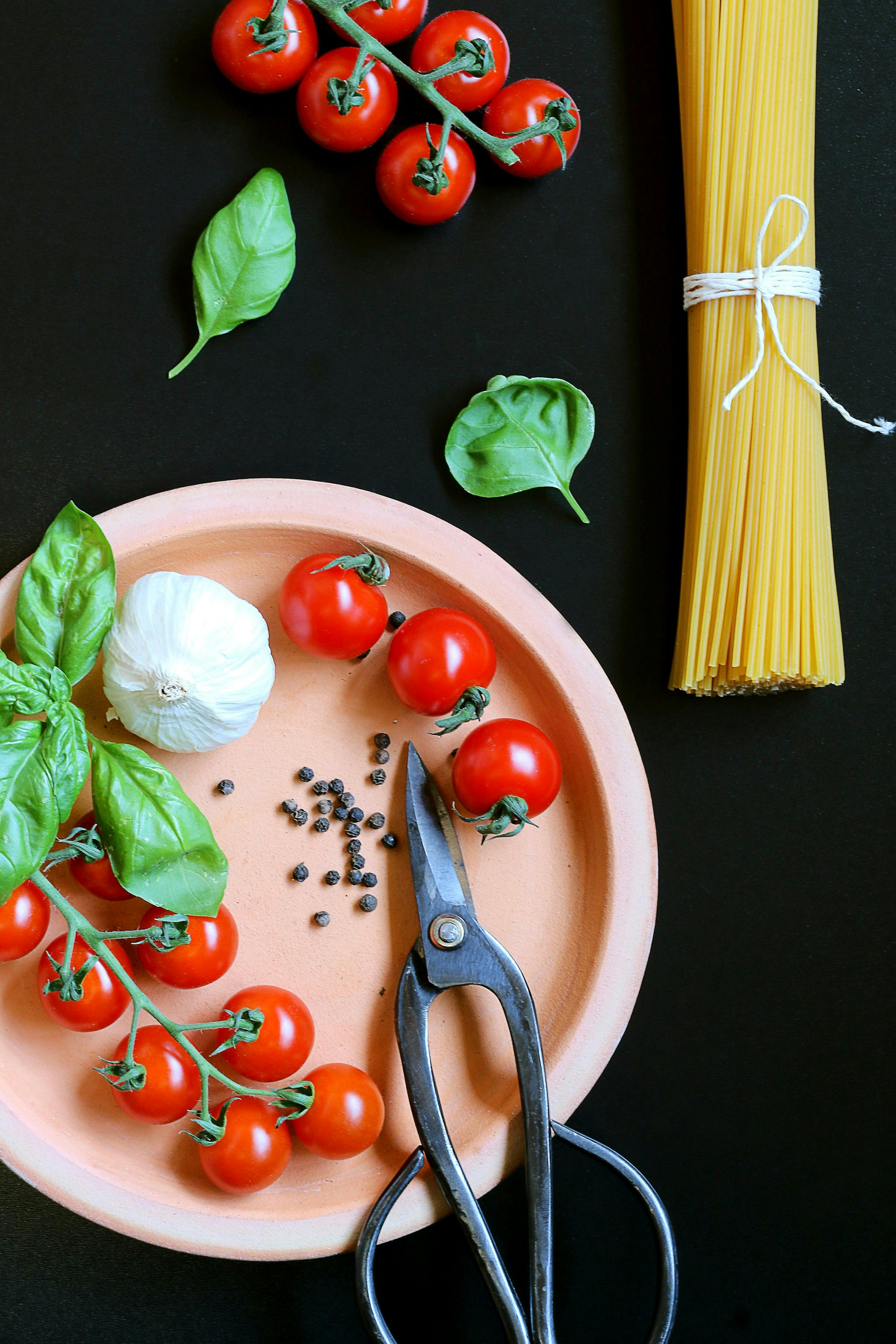 tomatoes basil and spaghetti on black background