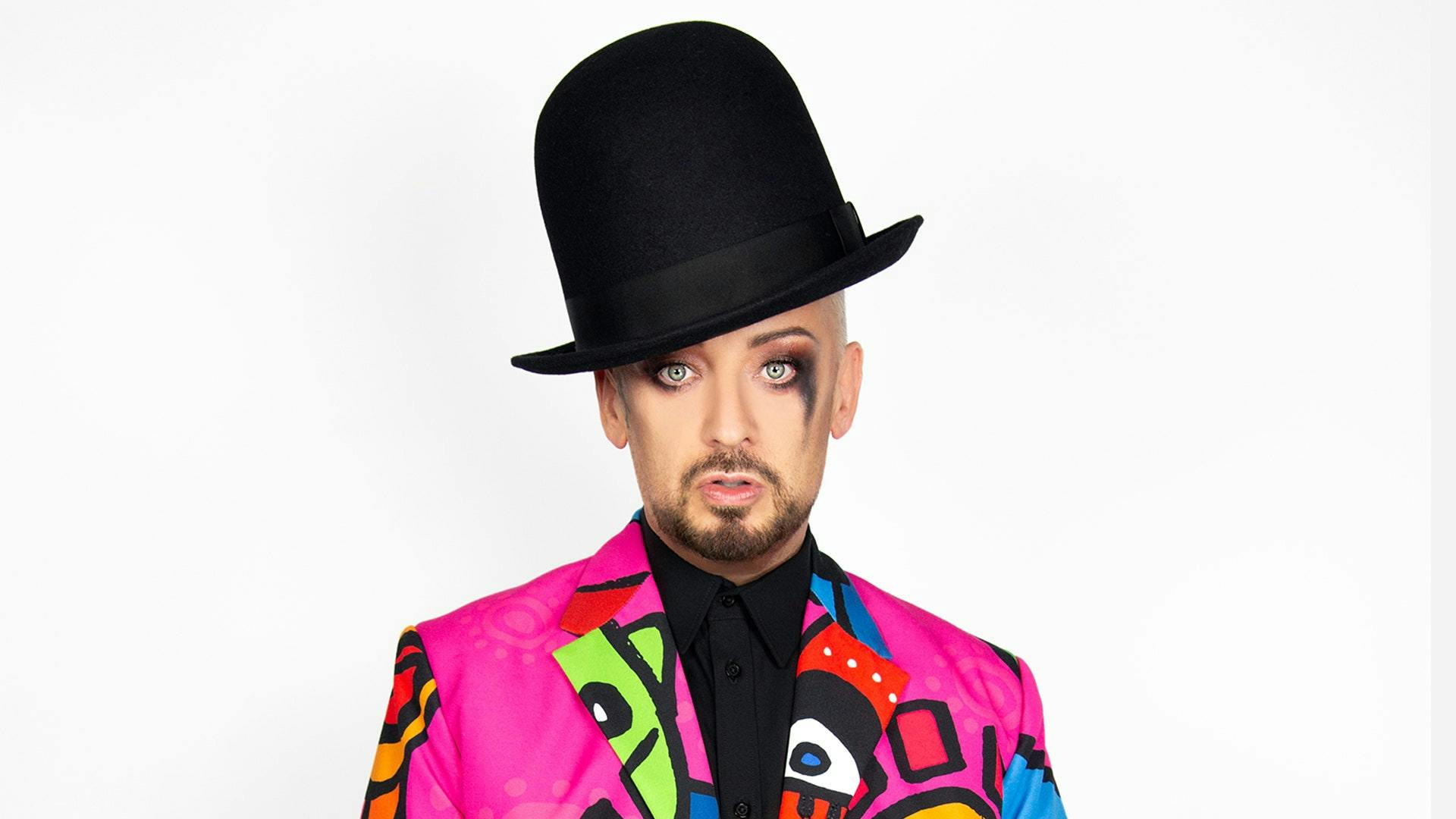 Boy George large black hat and pink jacket