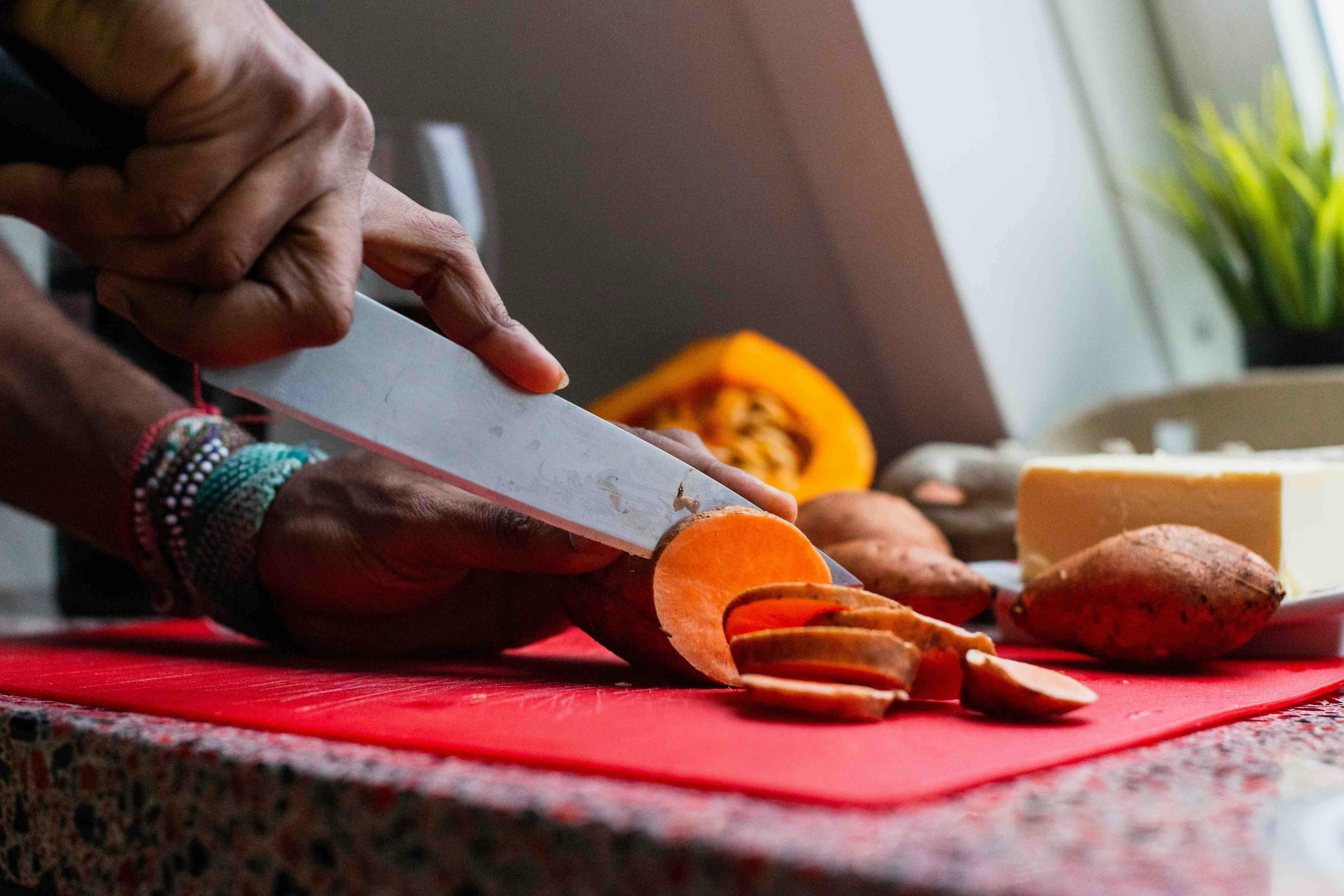 hands chopping sweet potatoes 