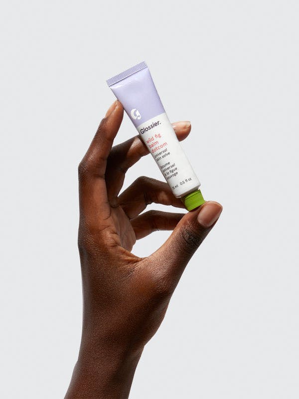 person holding glossier balm