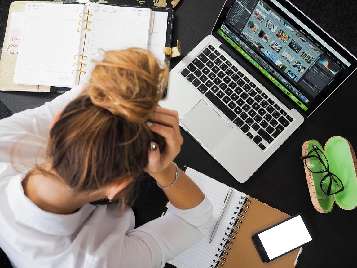 woman with head in hands over a laptop