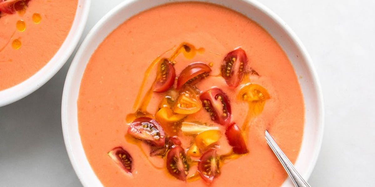 gazpacho soup in white bowl with metal spoon