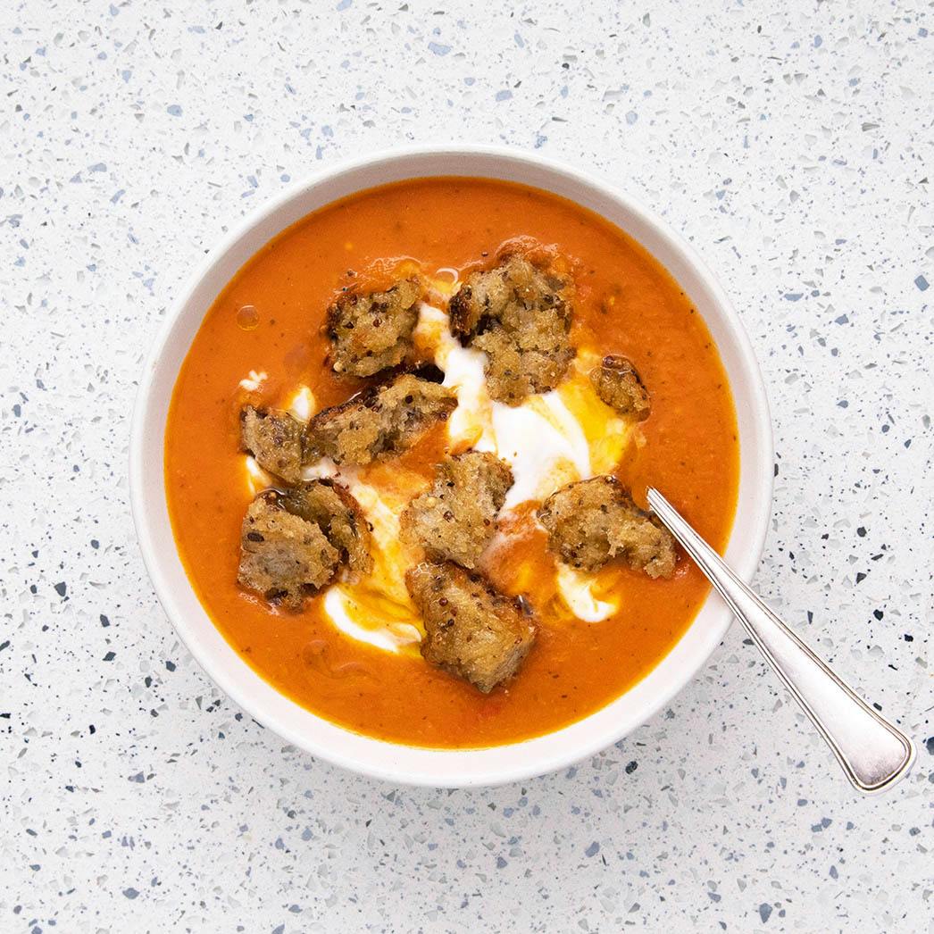 tomato and tamrind soup in white bowl with spoon