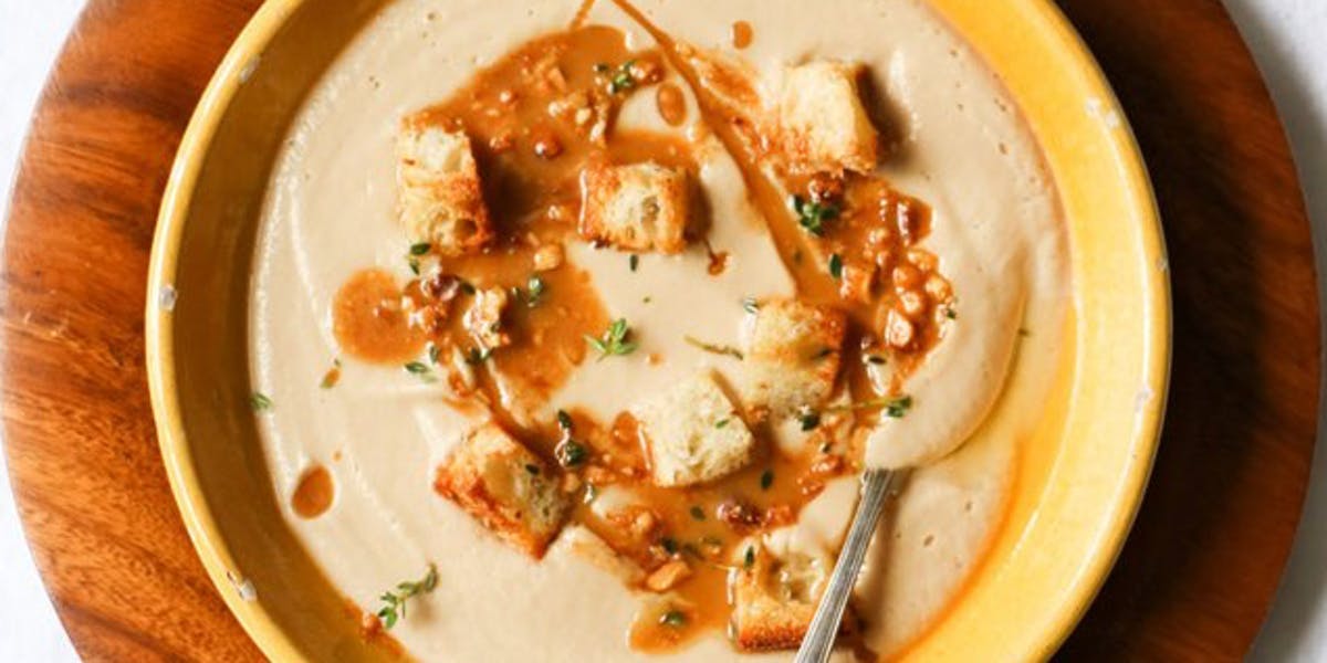 roasted cauliflower soup in yellow bowl on brown table