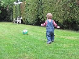 toddler chasing ball through garden 