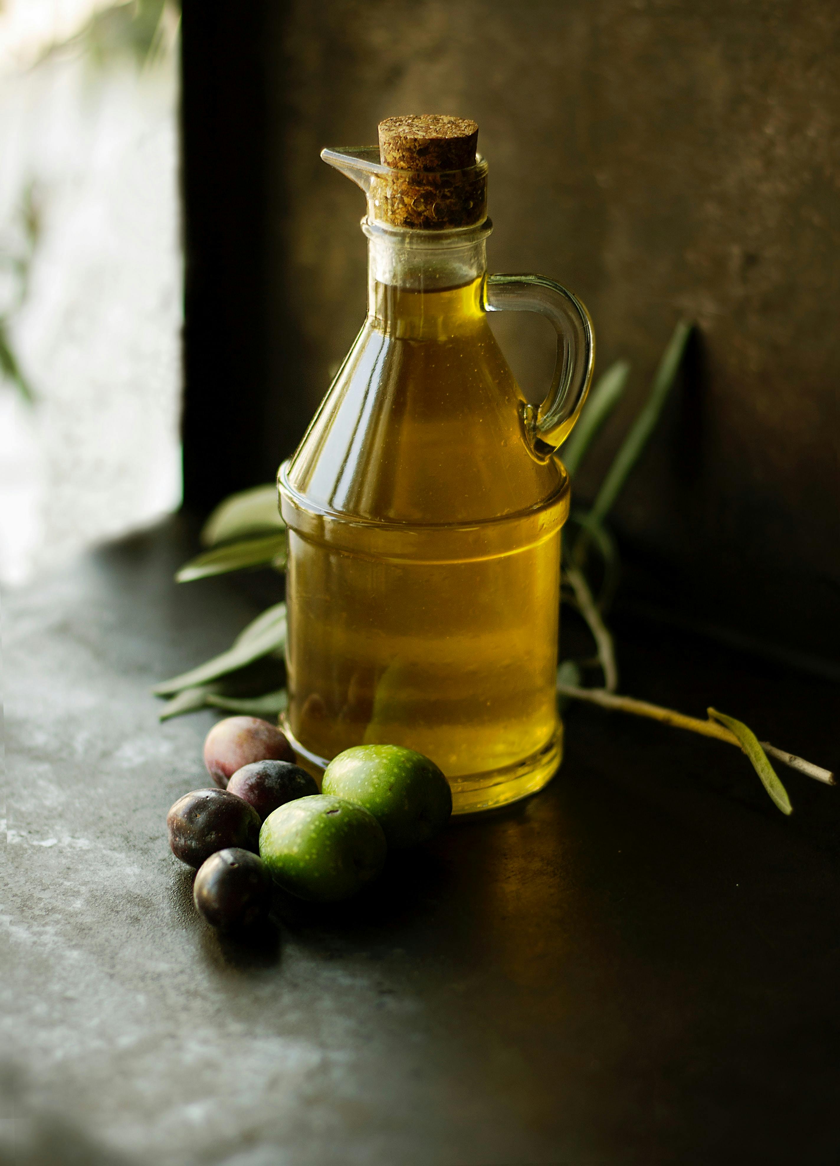 picture of jar of olive oil on table with fresh olive