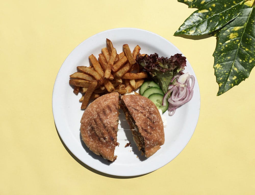 burger and chips on white plate on yellow background