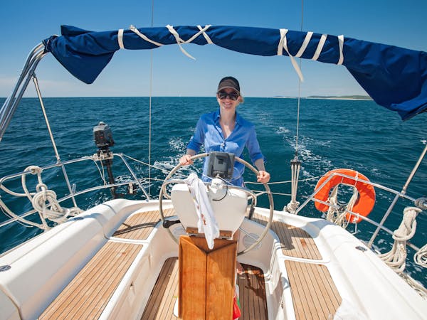 Young woman standing at the helm of a chartered yacht