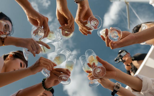 Friends cheers with champagne glasses on a sunny day the start of a sailing trip on a chartered yacht