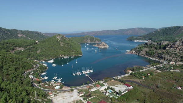 Aerial view of charter yachts berthed at Kiz kumu beach with green mountains surrounding them in Mugla, Turkey