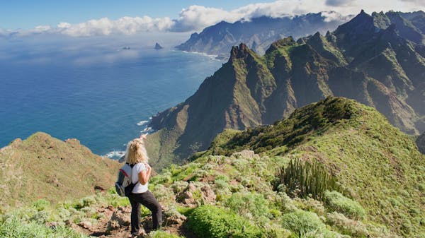 Woman hiker watching beautiful costal scenery in Tenerife, Canary Islands, Spain. Western coast view including mount Anaga