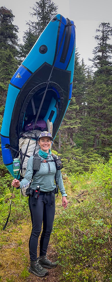 Alpine Fit's Jen carrying her packraft on her back while portaging. 