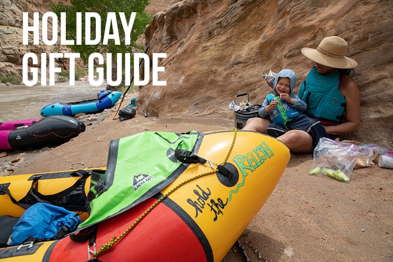 Holiday Gift Guide - mom and child sitting on the beach next to a packraft.