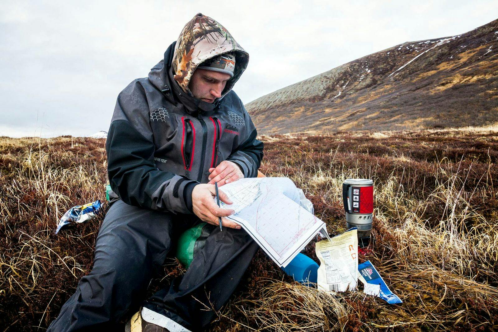 Bjorn Dihle reviews a topo map to plan the next day&#x2019;s route while boiling water for the evening meal.