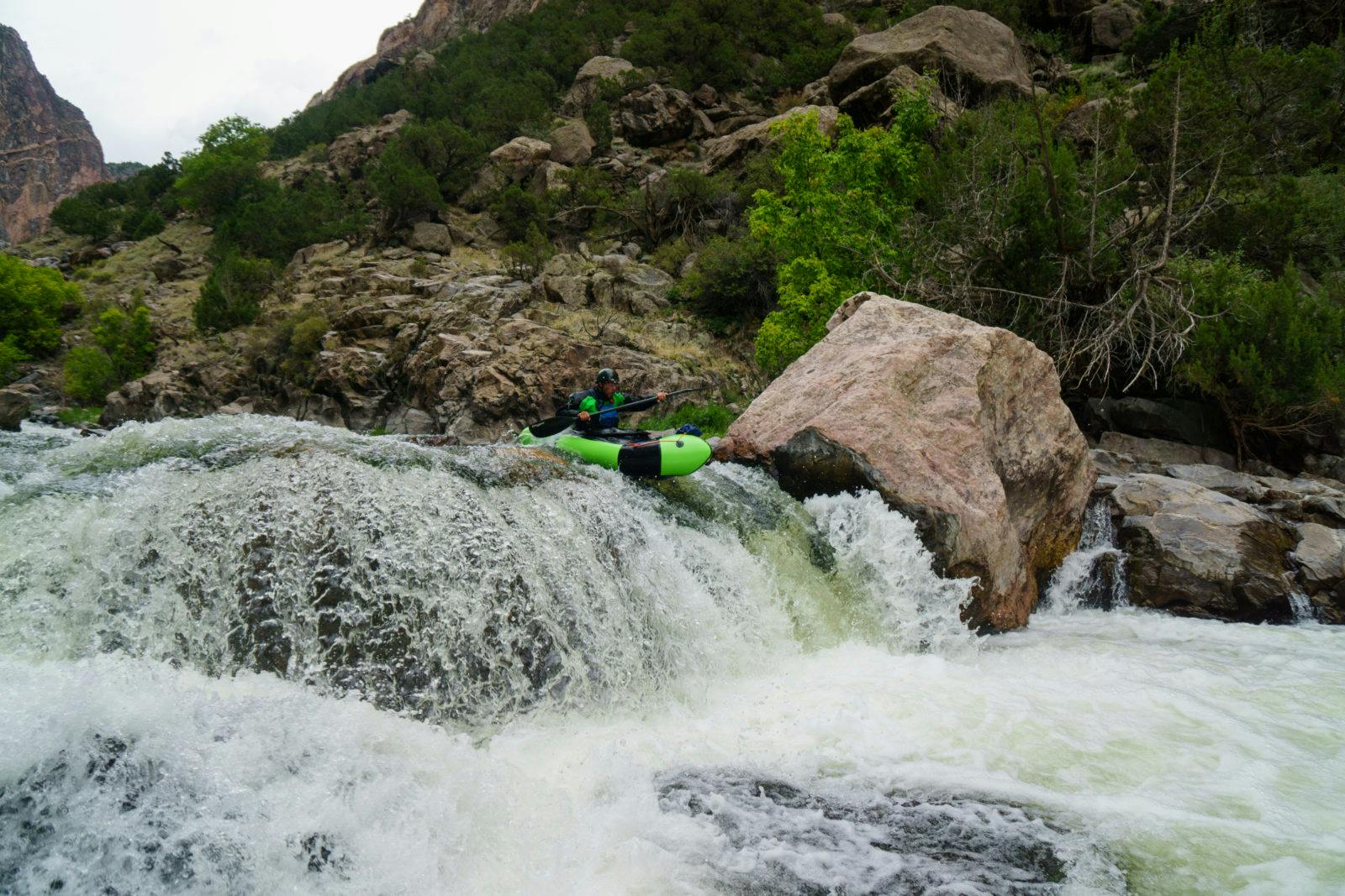 A lime green Gnarwhal launches off a waterfall in the Black Canyon. Photo by Thor Tingey. 