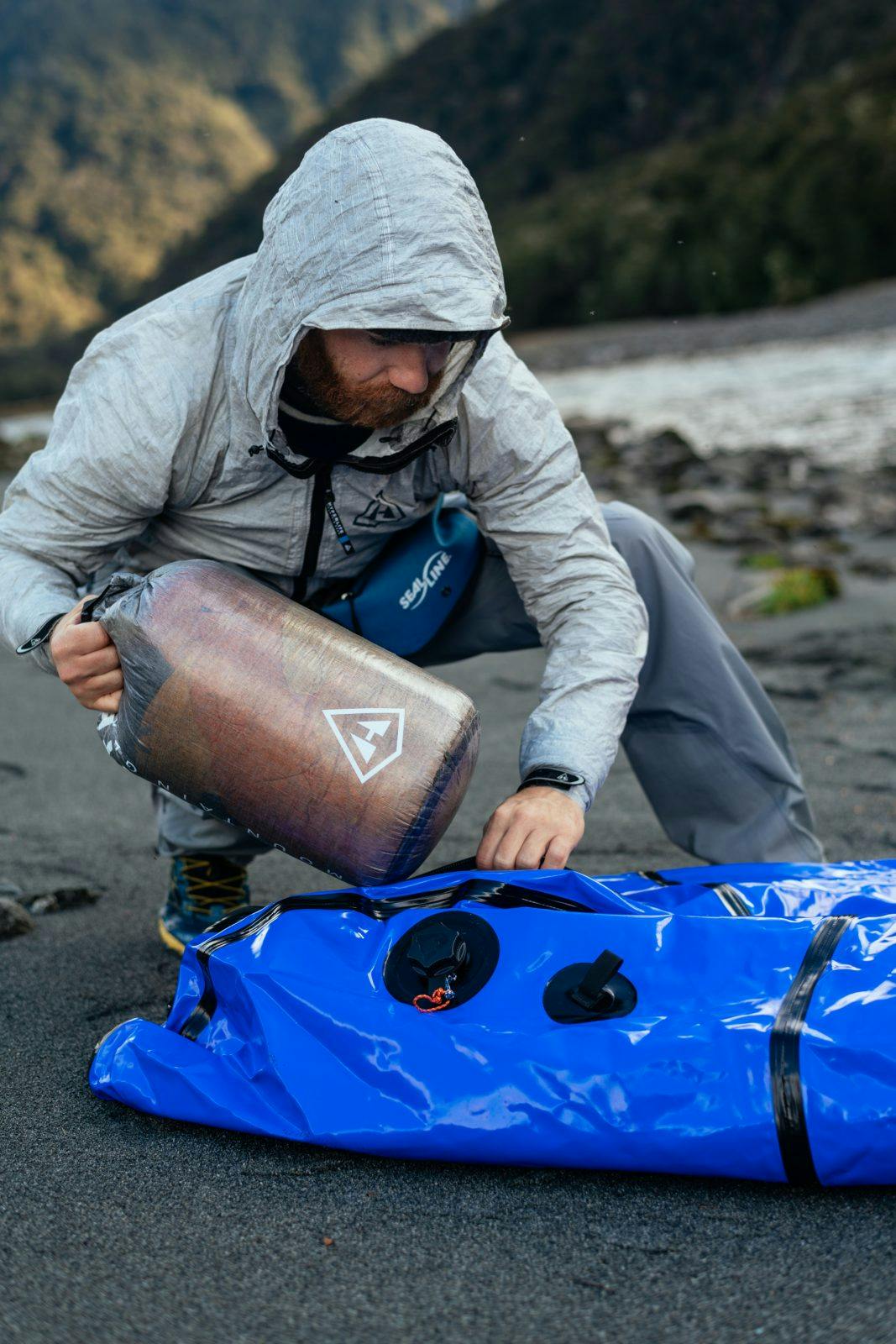 Adventurer Chris Brinlee Jr., one of the newest adopters of the packraft, stuffs his with an HMG Stuff Sack while on the Wilkin River, New Zealand.