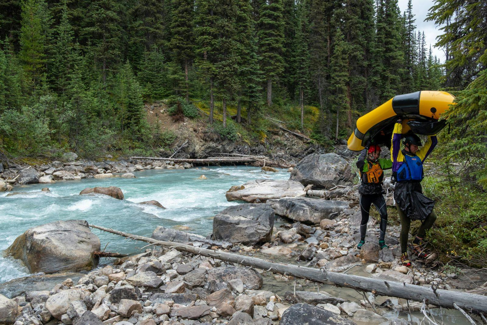 Laura and Coburn experimenting with portage techniques for loaded packrafts. A three-meter drop with a log jam lay just around the corner. Photo by Rachel Davies