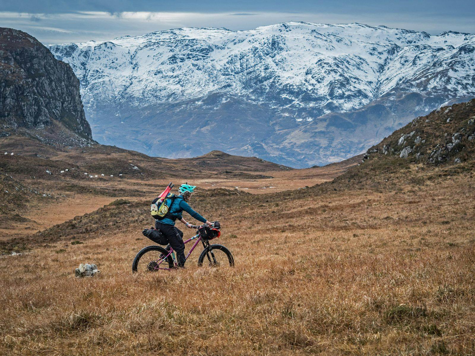 Annie Lloyd-Evans peddling across the Scottish Highlands with her raft rolled on the handlebars. Photo: Huw Oliver.