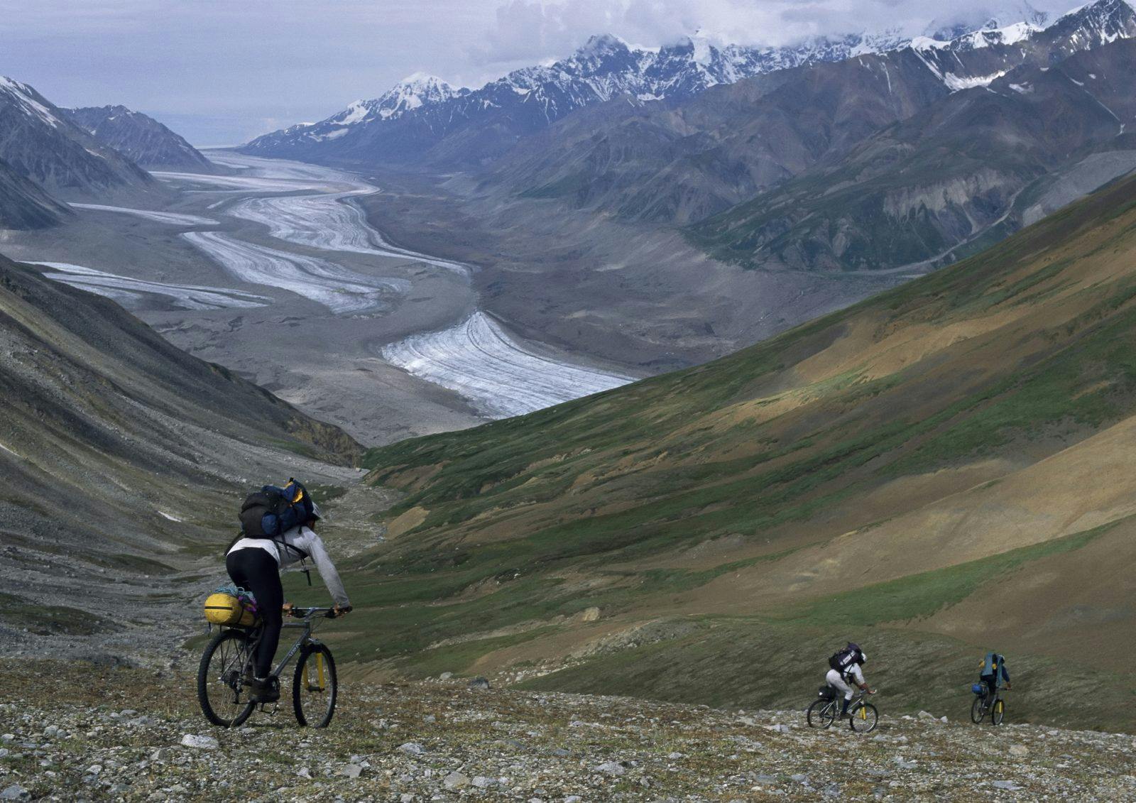 Expedition members descend a thousand feet toward the Black Rapids Glacier by bike. Photo by Bill Hatcher.Expedition members descend a thousand feet toward the Black Rapids Glacier by bike. Photo by Bill Hatcher.