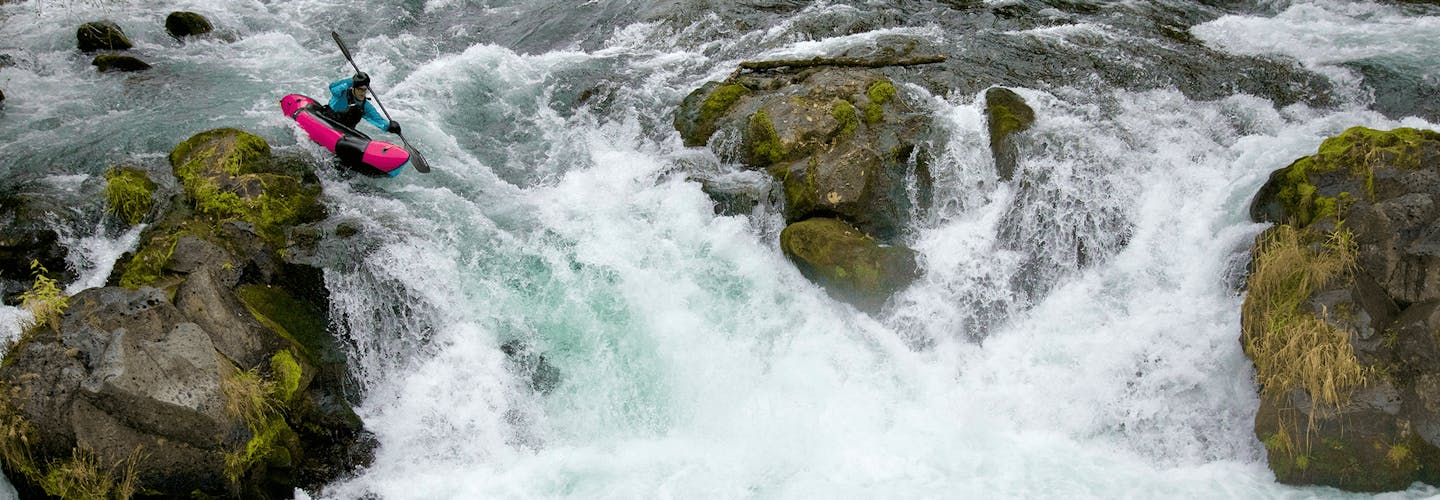 Alpacka Raft's new Mage packraft being paddled around big boulders on a waterfall.