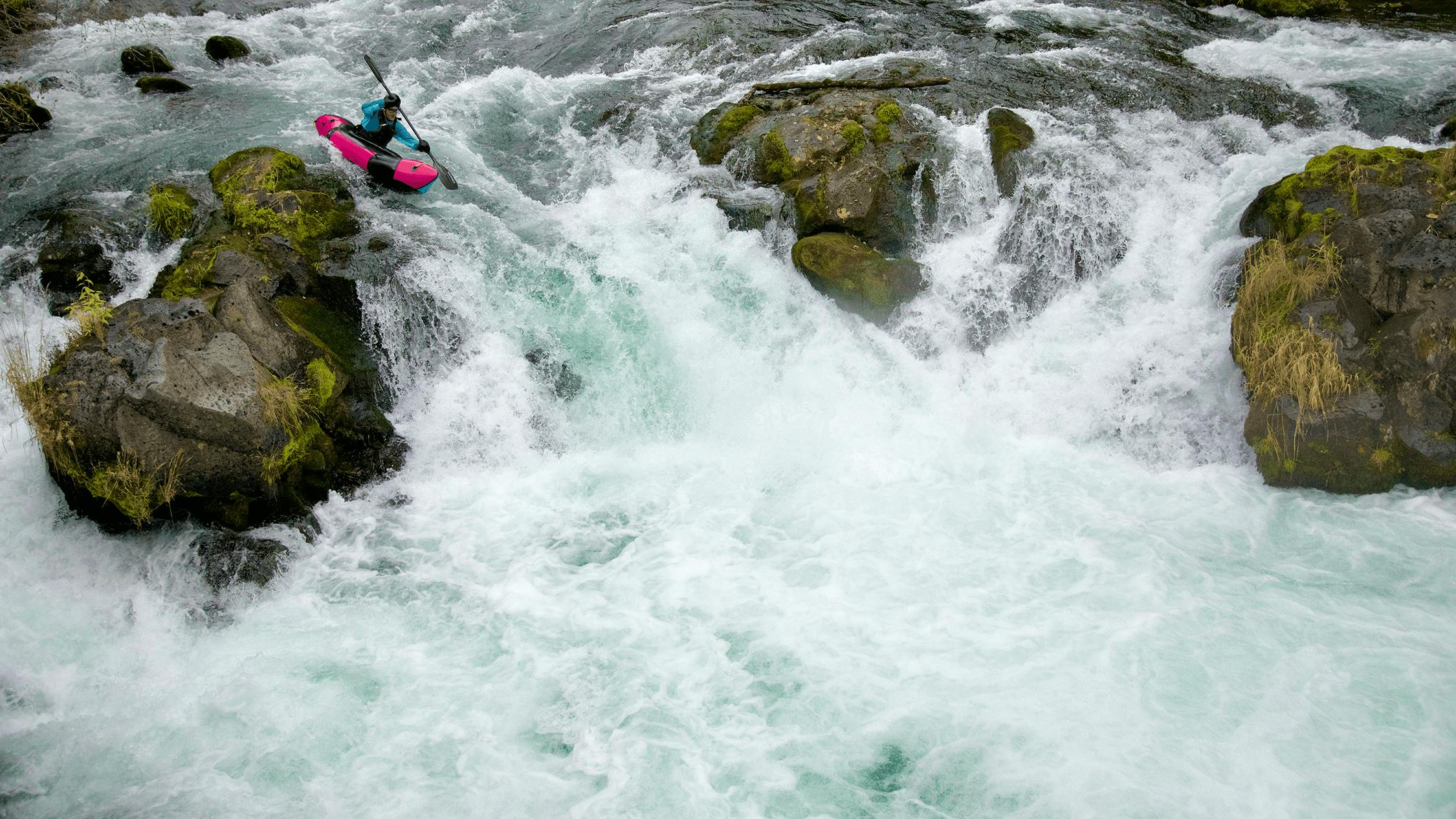 Alpacka Raft's new Mage packraft being paddled around big boulders on a waterfall.