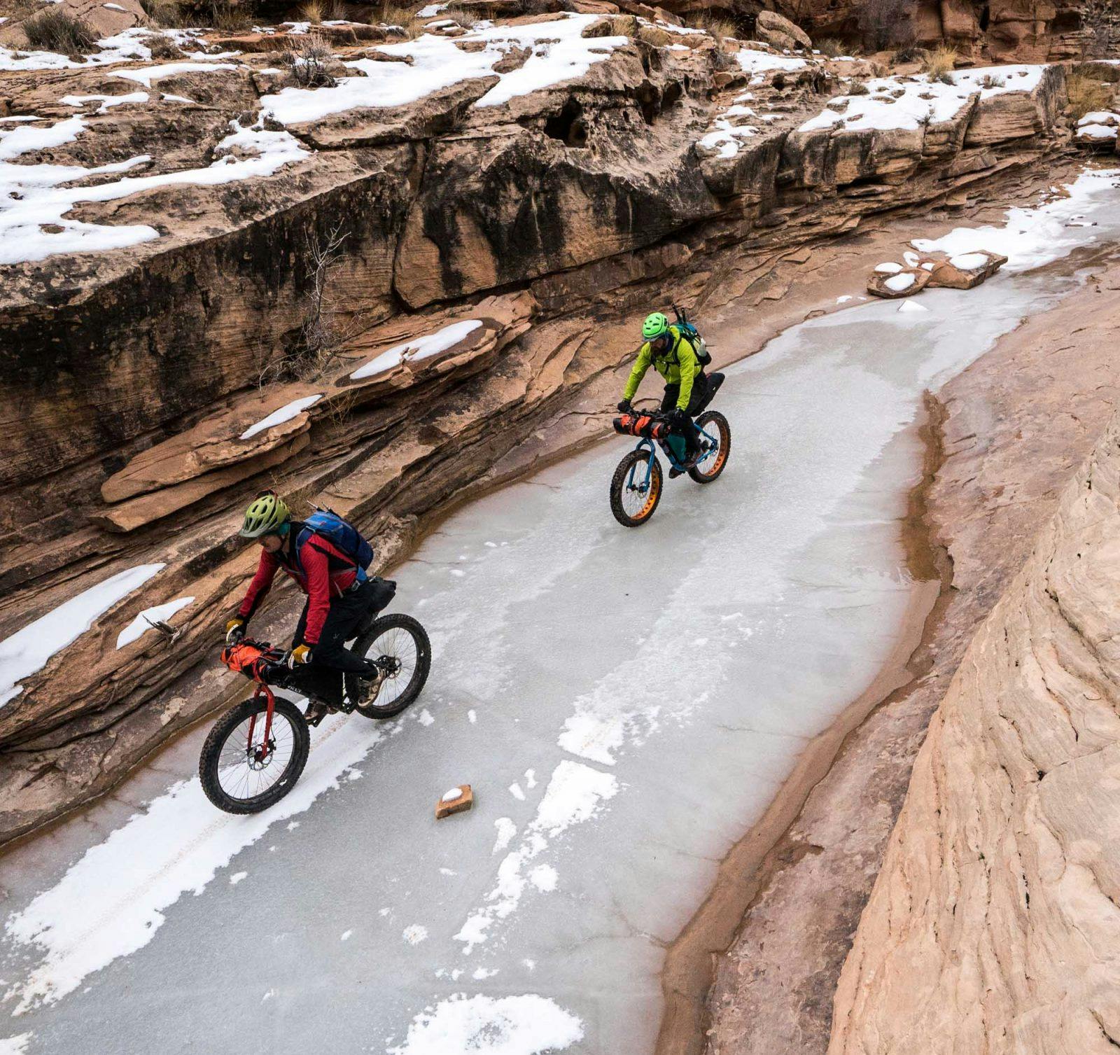 Mike Curiak (in front) and CEO Thor Tingey riding ice en route to the Green River, with the new Caribou Packraft lashed to the handlebars. Photo by Steve &quot;Doom&quot; Fassbinder.