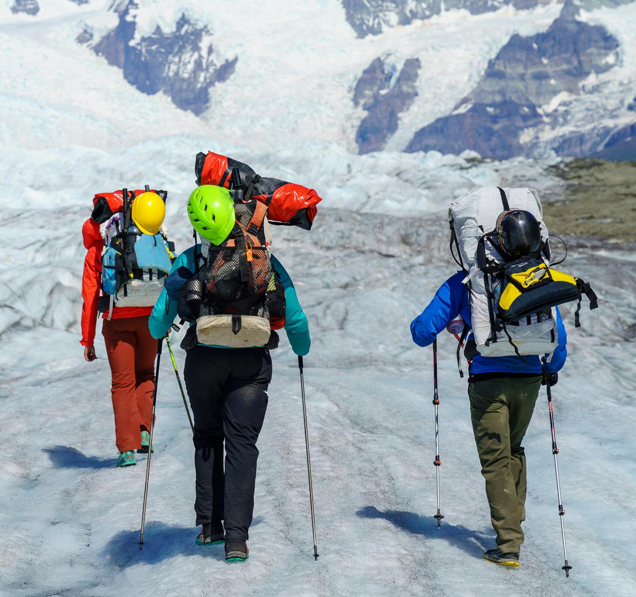 People hiking with packrafts over snowcovered landscape